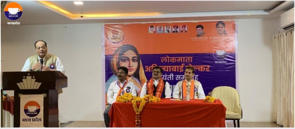 Dr. Atul Malikram speaking at a podium during a worker conference organized by Apna Dal (S) in Madhya Pradesh, with party leaders R.B. Singh Patel and Dr. Akhilesh Patel seated behind a decorated table, emphasizing the party's focus on social justice and expansion.