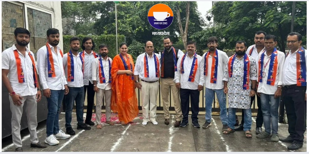 Group photo of Apna Dal (S) members in Indore standing in front of the party office with the national flag, wearing orange and blue sashes, celebrating the 79th Independence Day and pledging support for backward, dalit, and tribal communities.